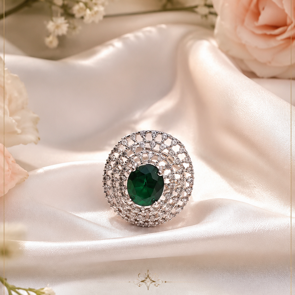 Luxury emerald green halo statement ring with crystal detailing on satin background