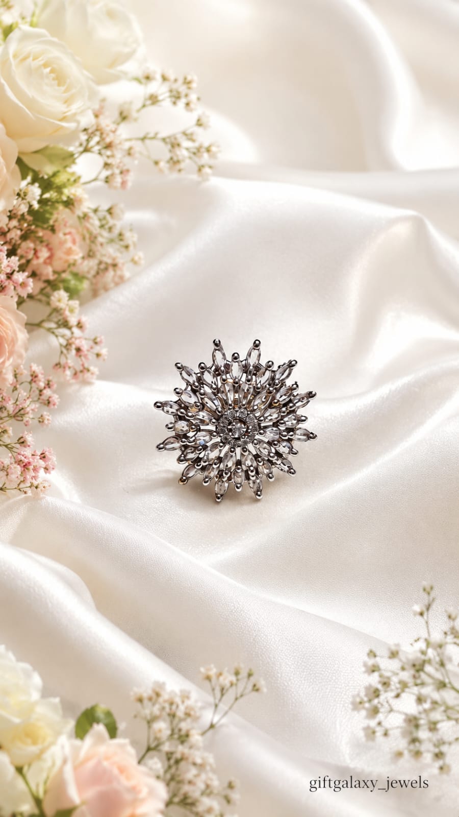 Hand wearing elegant silver crystal floral statement ring with pastel lavender nails and soft floral background.