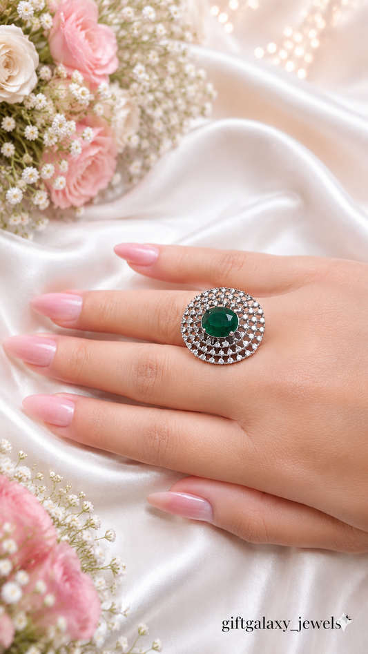 Luxury emerald green halo statement ring with crystal detailing on satin background