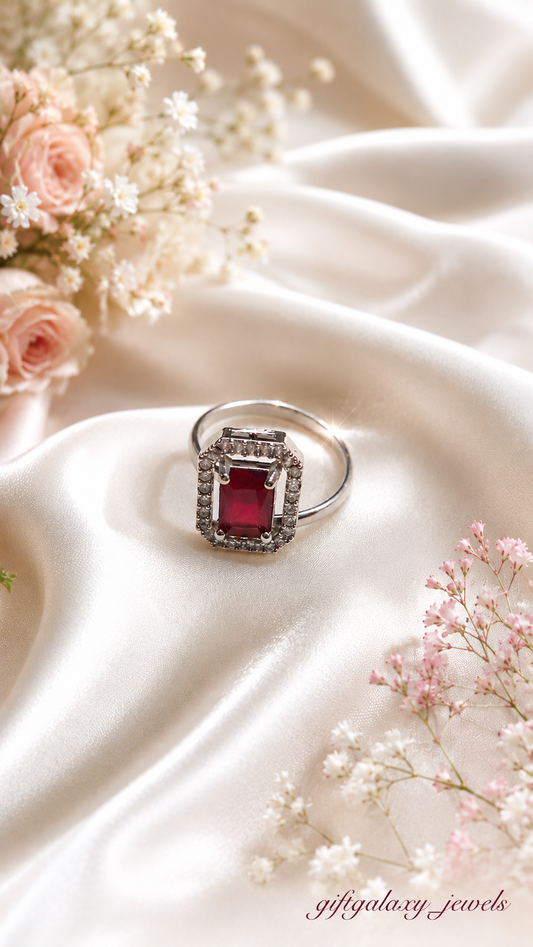 red emerald cut halo statement ring with silver tone adjustable band on satin background